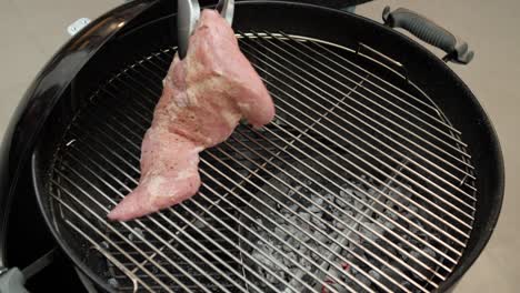 A-pork-steak-is-added-to-a-hot-charcoal-grill