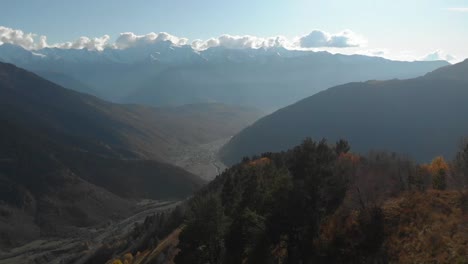 Aerial-slow-forward-moving-clip-of-a-Georgian-valley-and-many-mountains,-during-autumn