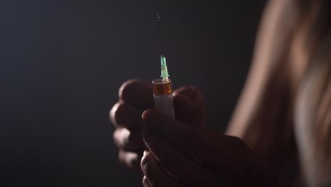 Close-up-of-a-person-preparing-a-disposable-syringe-by-flicking-it-with-fingers-in-slow-motion-and-the-liquid-splattering