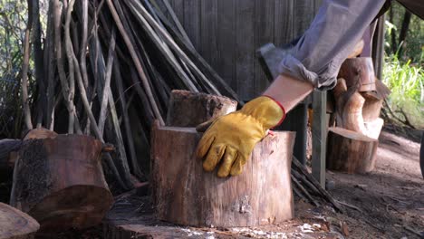 Man-picks-up-axe-and-splits-logs-by-wood-store-for-winter-fuel---close-up-of-axe,-log,-man-at-work,-legs,-work-boots-and-work-gloves---4K-59