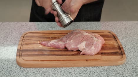 Closeup-of-a-chef-adding-pepper-to-a-raw-pork-beef