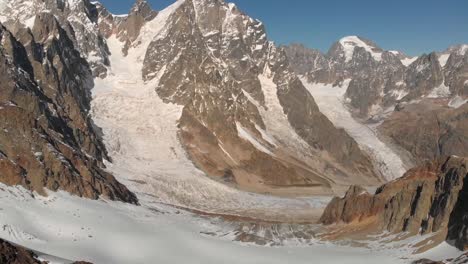Slow-aerial-clip-of-the-Mount-Ushba-glacier,-at-the-top-of-the-mountain,-during-a-sunny-day