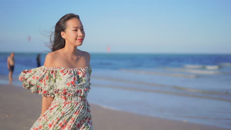Slow-motion-of-Asian-lady-walking-along-the-beach-in-Thailand-wearing-a-long-sundress,-blurred-background
