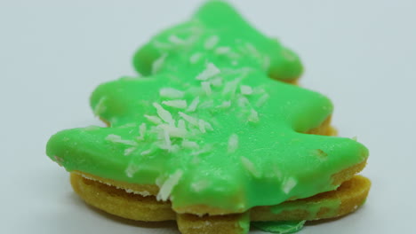 Close-up-macro-zoom-in-view-of-christmas-cookies-in-the-form-of-green-Christmas-tree-with-coconut-on-white-background-in-slow-motion-capture