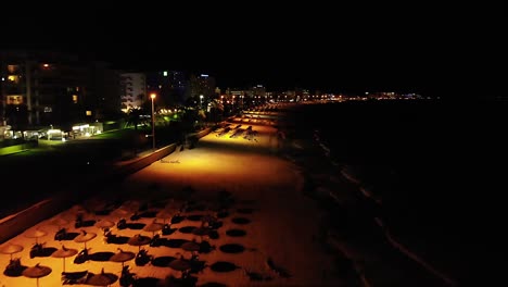 Drone-flight-over-an-empty-beach-in-Mallorca,-Spain-at-nighttime