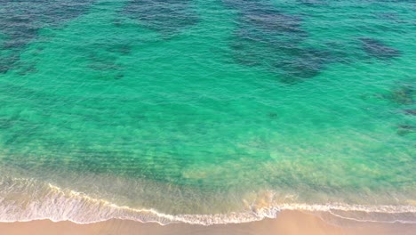 Aerial-view-of-tropical-white-sandy-beach-with-soft-waves-hitting-the-shore