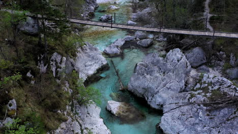 Aerial-view-of-the-soča-river-and-a-footbridge-spanning-across-it