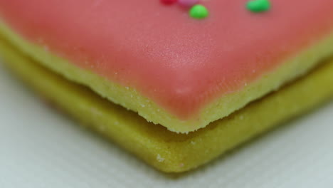 Close-up-macro-center-view-of-Christmas-cookies-in-the-form-of-a-pink-heart-with-icing-and-decorated-with-colorful-balls-and-its-corpus-in-close-up-shot-in-slow-motion-capture
