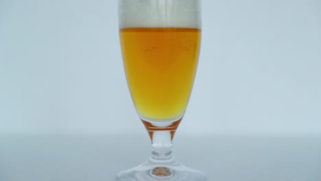Makro-Nahaufnahme-Eines-Vollen-Glases-Bier,-In-Dem-Sich-Blasen-Langsam-Zur-Spitze-Eines-Glases-In-Schöner-Bierfarbe-Mit-Schaum-Oben-In-Zeitlupenaufnahme-Mit-120-Fps-Bewegen
