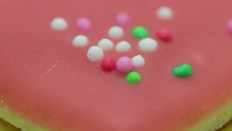 Close-up-zoom-move-macro-view-of-Christmas-cookies-in-the-form-of-a-pink-heart-with-icing-and-decorated-with-colorful-balls-and-its-corpus-in-close-up-shot-in-slow-motion-capture
