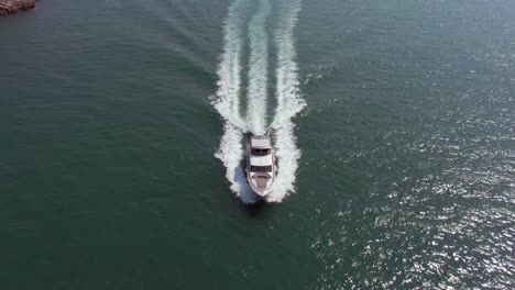 Large-Yacht-crossing-the-frame-heading-to-port-leaving-a-beautiful-wake-behind,-Tilt-down-aerial-view