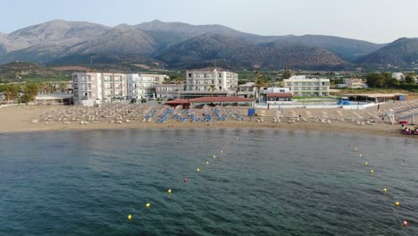 Tourist-Unter-Sonnenschirm-Am-überfüllten-Griechischen-Strand,-Wunderschönes-Türkisfarbenes-Und-Blaues-Wasser