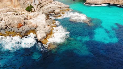 Aerial-shot-of-sea-waves-crash-into-coastline-cliffs-Mallorca,-Spain