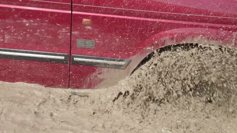A-red-vehicle-drives-through-deep-muddy-waters-in-slow-motion