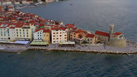 Aerial-shot-of-Piran-lighthouse-and-the-amazing-town-at-golden-hour,-Slovenia