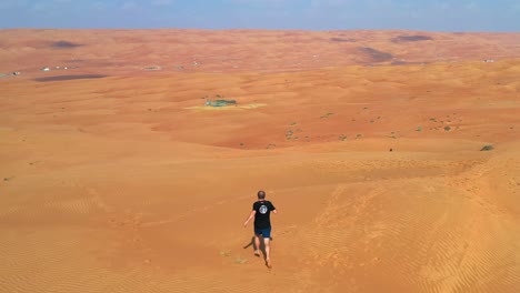 Man-running-barefoot-on-the-sands-of-an-endless-vast-barren-desert-with-drone-controller-in-his-hand