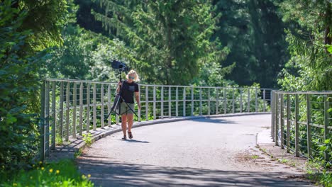 Beautiful-blonde-woman-carrying-photography-equipment-in-the-middle-of-nature