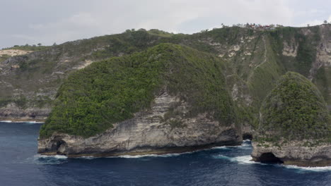 Slow-pivot-around-peninsula-at-Kelingking-Beach-with-steep-cliffs-on-a-cloudy-day,-Nusa-Penida,-Indonesia