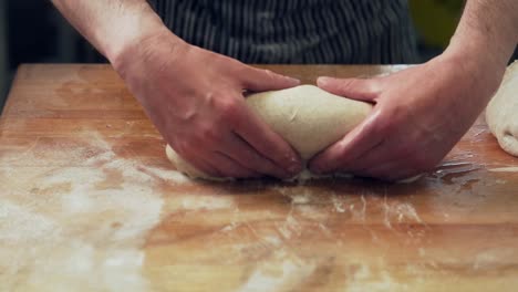 closeup,-baker's-hands-knead-bread-dough-and-spread-out-into-shape