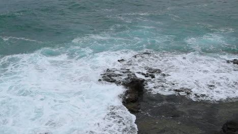 Wellen,-Die-In-Eine-Felsformation-Nahe-Der-Küste-Einer-Großen-Welle-Schlagen,-Die-Sich-Auf-Steinen-An-Den-Seiten-Bricht,-Aufgenommen-Mit-Normaler-Geschwindigkeit-Bei-24-Fps