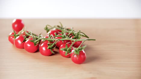 Un-Montón-De-Tomates-Cherry-Frescos-Caen-Sobre-Una-Mesa-Con-Fondo-Blanco,-Cámara-Lenta