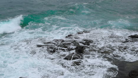 Wellen,-Die-In-Eine-Felsformation-Nahe-Der-Küste-Einer-Großen-Welle-Schlagen,-Die-über-Steine-An-Den-Seiten-Bricht,-In-Zeitlupenaufnahme-Mit-120-Fps