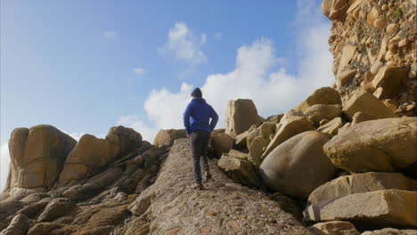 Hiking-up-rocky-boulder-filled-beach-path-in-Porth-Nanven,-Cornwall,-upward-view