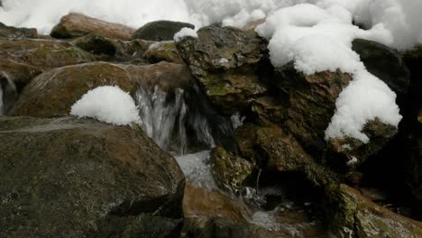 Ein-Bach,-Der-Zwischen-Steinen-Im-Schnee-Fließt