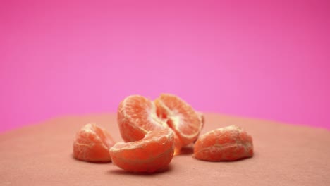 Ripe-peeled-mandarin,-rotate-on-pink-and-old-paper-background-4k-video-with-color-correction