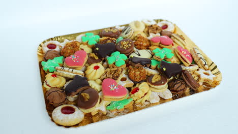 Hand-taking-Christmas-cookies,-which-is-laid-on-a-gold-plate-decorated-and-stacked-wearing-different-colors-of-species-and-sizes-in-the-normal-speed-motion-capture-at-24fps
