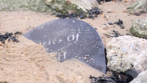 Granit-Grabstein-Teilweise-Im-Sand-An-Einem-Strand-Begraben