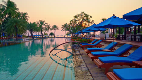 bed-pool-and-umbrella-around-swimming-pool-with-sunset-or-sunrise-sky