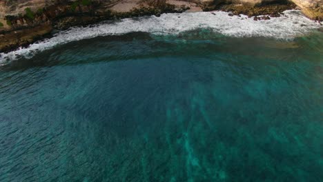 Aerial-view-Moving-forward-shot,-scenic-view-of-the-sea-meeting-the-shore-of-the-Tanjung-Ringgit-cliff