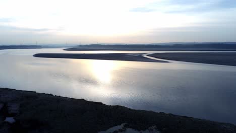 Idyllic-aerial-view-rising-over-hazy-British-coastal-river-waterway-at-sunrise
