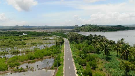 Aerial-view-moving-forward-shot,-scenic-view-of-southern-road-and-rice-fields,-bridge-connecting-Lombok-islands
