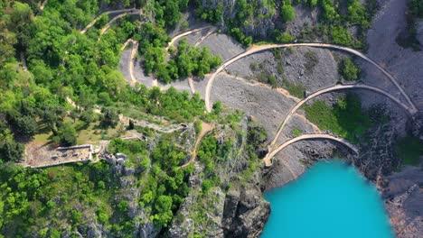 Aerial-of-a-curvy-trail-coming-from-Imotski-town-leading-to-Blue-Lake,-a-popular-attraction-in-Croatia