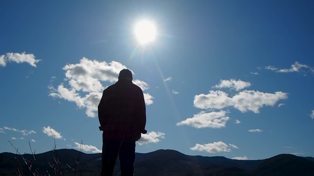 Premium stock video - Silhouette of man looking at sun and clouds with ...