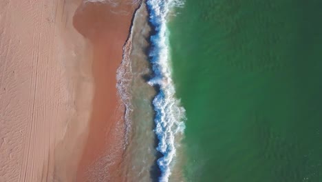Aerial-tilt-down-shot-to-waves-reaching-a-sandy-beach-in-the-south-of-Spain