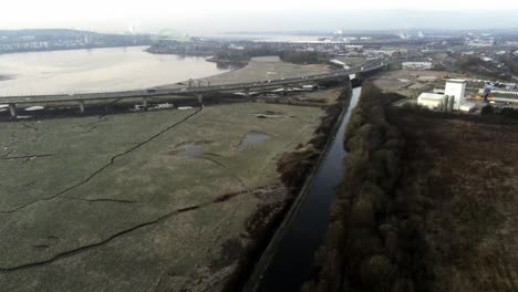 River-marsh-land-coast-pull-away-from-commuter-traffic-crossing-bridge-uk