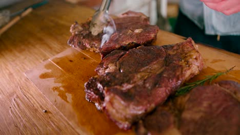 View-of-a-man-arranging-the-slices-of-smoky-hot-steak-on-a-wooden-table