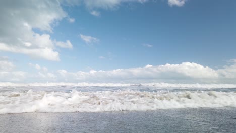 Slowmo-Ocean-Wave-Rolls-In-to-Camera-with-Picturesque-Cloudy-Sky