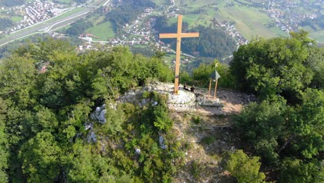 Unrecognizable-hikers-take-a-break-under-the-gigantic-wooden-cross-of-a-mountain-peak-in-the-clearing-of-a-forest