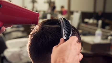 barber-dries-hair-dryer-in-barbershop