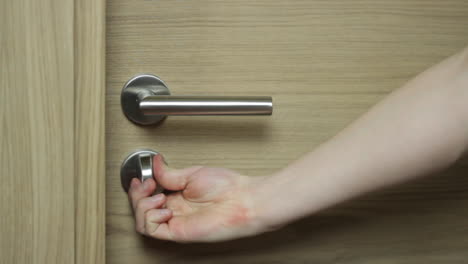 Close-up-of-Caucasian-right-hand-closes-wooden-door-and-locks-chrome-deadbolt