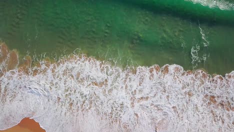 Aerial-still-shot-of-big-waves-crashing-into-a-sandy-beach
