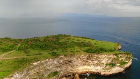 Aerial-view-moving-forward-shot,-above-the-green-cliff-of-Tanjung-Ringgit,-scenic-view-of-the-sea-of-Lombok-Indonesia