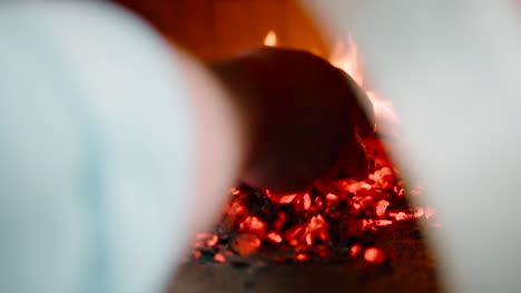 Close-up-view-of-a-man-placing-the-steak-on-a-firewood-oven