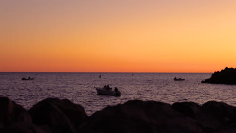 Die-Silhouette-Eines-Fisches-Auf-Einem-Kleinen-Boot-Vor-Der-Küste-Während-Eines-Orangefarbenen-Sonnenuntergangs,-Während-Sie-Angelruten-In-Den-Ozean-Werfen-Und-Das-Grand-Canary-Island-Valley-Fischen-4K-Zeitlupenaufnahme-Mit-60-Fps
