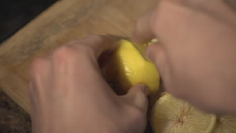 A-person-hands-cutting-a-fresh-lemon-into-pieces-on-a-cutting-board---Close-up-shot