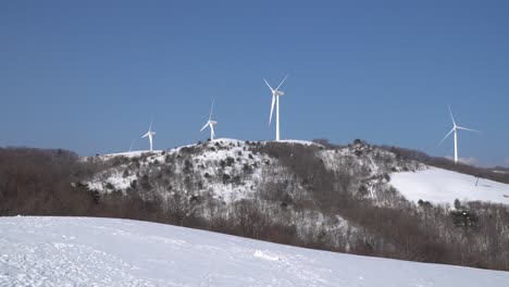 Wind-power-turbines-farm-is-seen-in-the-snow-covered-mountain,-South-Korea